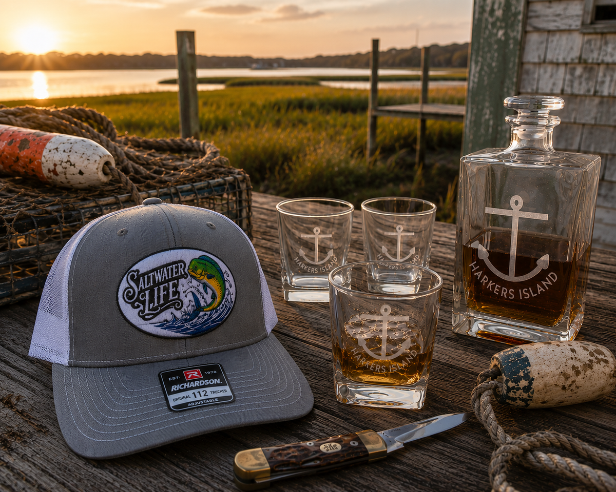 Hat, glasses, and decanter on a table with other misc items near a body of water