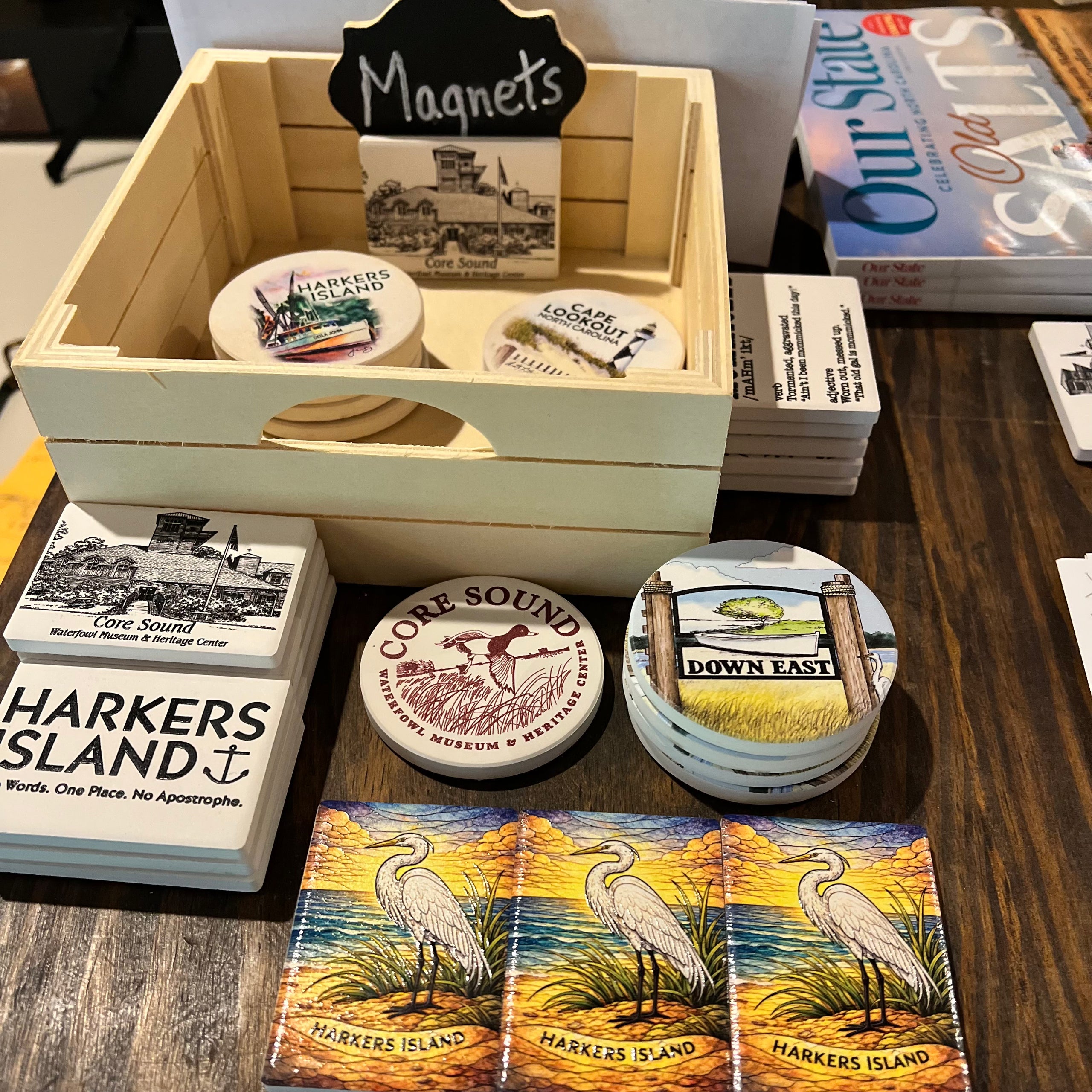 Collection of magnets and coasters with scenic designs on a wooden surface.