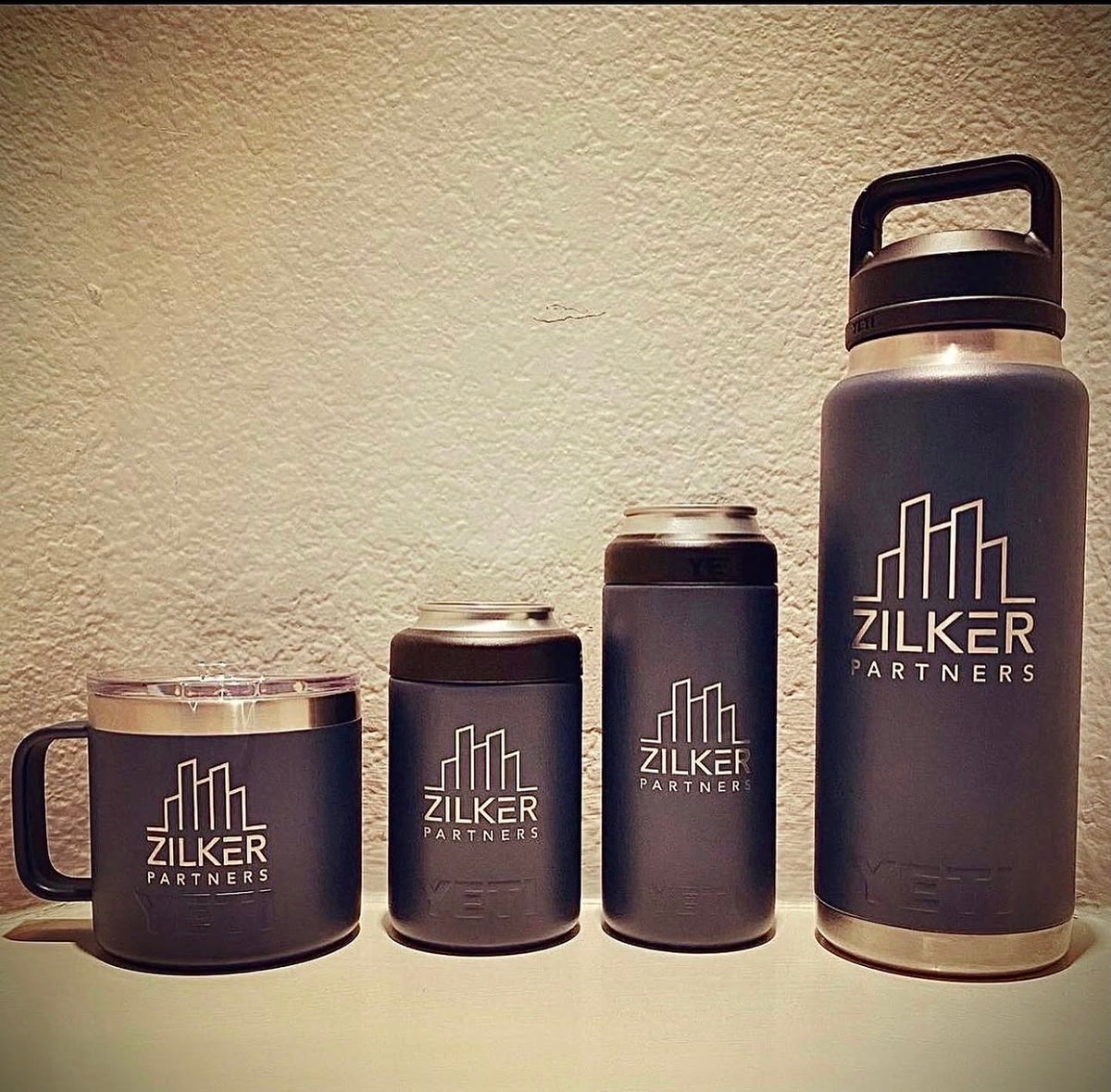 Assorted blue powder coated drinkware with the Zilker Partners logo engraved